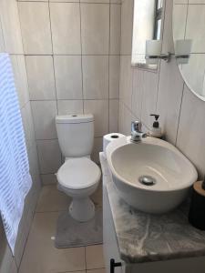 a bathroom with a white toilet and a sink at Ocean Haven in Walvis Bay +3 photos