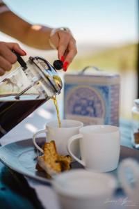 a person pouring coffee into cups on a table at Uitkyk Kliphuisie in Uniondale +15 photos