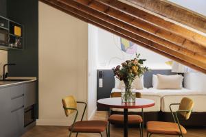 a room with a bed and a table with a vase of flowers at Blume Cruz Suites in Madrid