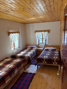 two beds in a room with wooden floors and windows at Guest House Prebibaj in Curraj i Epërm