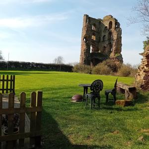 a table and chairs in a field with a castle at The Shepherd's Hut in Sheriff Hutton +11 photos