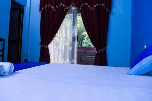 1 dormitorio con 1 cama con cortinas rojas y ventana en Shrine Inn, en Kandy
