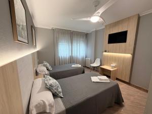 a hotel room with two beds and a television at Pensión Atenea & Via Romana - Grupo Arcanos in Caldas de Reis