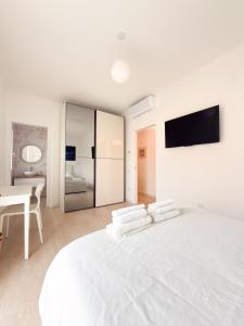 a white bedroom with a large white bed and a table at Riganvì Affittacamere Sestu in Sestu