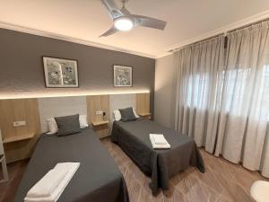 a bedroom with two beds and a ceiling fan at Pensión Atenea & Via Romana - Grupo Arcanos in Caldas de Reis +18 photos