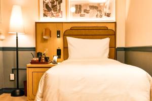 a bedroom with a white bed and a night stand with a lamp at Union Hotel in Toronto