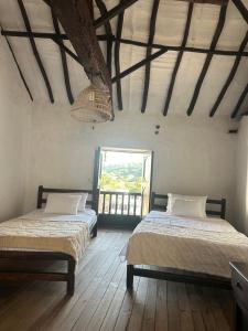 two beds in a room with a window at Casa casco urbano in San Gil