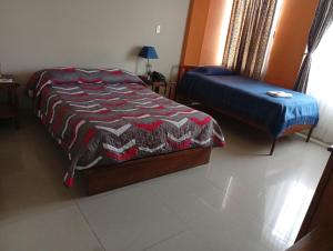 a bedroom with a bed and a ottoman in it at Hospedaje Las Garzas in Ibarra