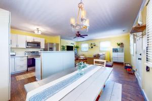 a living room with a table and a kitchen at Salty Tails in Kill Devil Hills