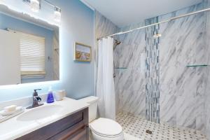 a bathroom with a shower and a toilet and a sink at Salty Tails in Kill Devil Hills +13 photos