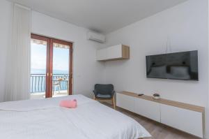 a bedroom with a bed with a television and a chair at Apartments Blue Adriatic View in Jesenice
