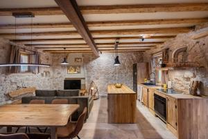 a kitchen and living room with stone walls and wooden ceilings at Apartment Heritage Stonehouse in Ugljan