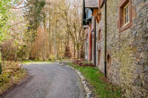 an empty road next to an old stone building at The Wood Wing Suite at Bellspool in Peebles +5 photos