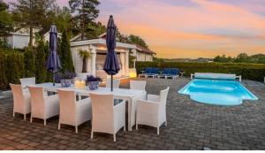 a table with chairs and umbrellas next to a pool at Spacious villa with heated pool and stunning view in Tokenes +23 photos