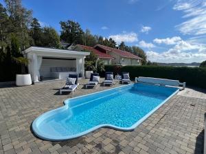 a swimming pool with lounge chairs next to a house at Spacious villa with heated pool and stunning view in Tokenes