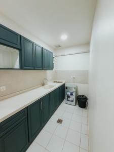 a kitchen with green cabinets and a white tile floor at شقق أونيسن للشقق المخدومة Onsen Serviced Apartments in Buraydah