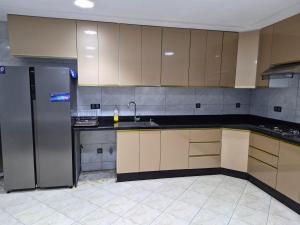 a kitchen with a stainless steel refrigerator and cabinets at Appartement villa spacieuse 200m2 terrasse prive grand jardin et piscine in Meknès