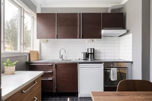 a kitchen with brown cabinets and a white appliance at Chic 2-Bedroom apartment on Lidingö in Lidingö