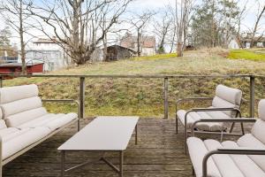 a balcony with white chairs and a table and a hill at Chic 2-Bedroom apartment on Lidingö in Lidingö +4 photos