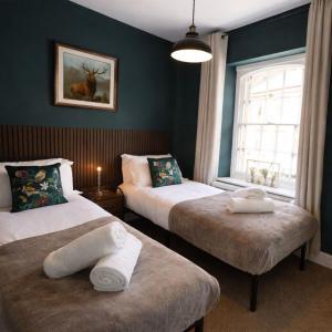 a bedroom with two beds and a window with a picture at The Counting House in Alnwick
