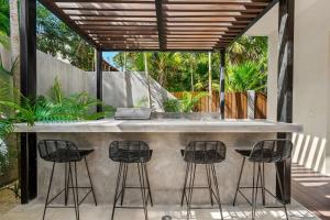 a outdoor kitchen with three bar stools at Piedras Luxe by Prestigia - Villa in Tulum