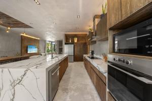 a large kitchen with marble counter tops and wooden cabinets at Twin Luxury Villas - Groups Prstigia MX in Tulum