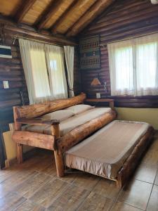 two beds in a room with wooden walls and windows at Alma de Algarrobo in San Javier