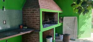 a green building with a brick oven in a room at Cabañas Donato in Colonia Benítez