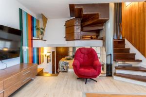 a red chair in a living room with stairs at BaruHaus triplex piscina y parking in Villamañán