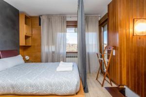 a bedroom with a bed and a chair and a window at BaruHaus triplex piscina y parking in Villamañán