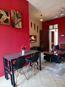 a living room with a table and chairs and a red wall at Catwalk Factory Apartment in Ukunda