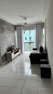 a bedroom with a bed and a couch and a window at Costa Suite Enseada in Guarujá