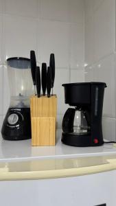 a kitchen counter with a coffee maker and knives at Costa Suite Enseada in Guarujá