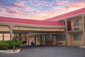 a building with a red roof with a parking lot at Tree Inn & Suites Albuquerque in Albuquerque