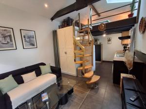 a living room with a couch and a spiral staircase at Studio indépendant avec jardinet in Tarnos