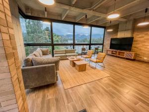a living room with couches and a tv and large windows at Upscale 2BR Countryside Suite | Stylish & Modern in El Retiro