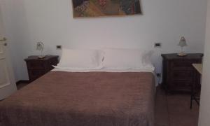 um quarto com uma cama com lençóis brancos e duas mesas de cabeceira em Appartamento Giardino Verde em Módena