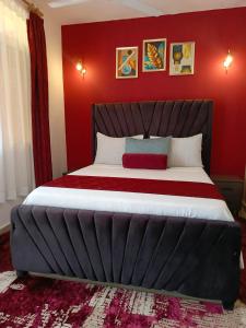 a bedroom with a large bed with red walls at Catwalk Factory Apartment in Ukunda