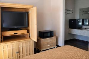 a bedroom with a television on a wooden cabinet at Tree Inn & Suites Albuquerque in Albuquerque