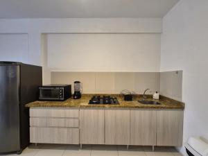 a kitchen with a counter top with a microwave and a sink at Cumbuco Residence #203 in Caucaia