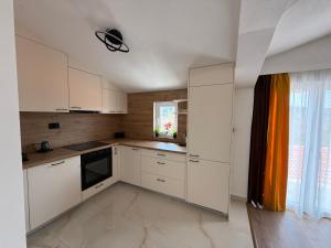 a kitchen with white cabinets and an orange curtain at Apartman Đole&Ljuba -Radanovići , Kotor in Ðuranovići