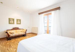 a white bedroom with a bed and a couch at Can Maro in Santa Margalida