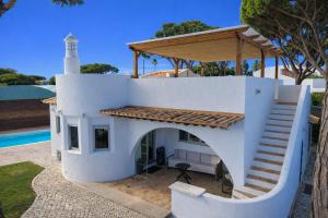a white house with a staircase leading to a lighthouse at Villa 7 - Vale do Lobo in Almancil