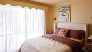 a bedroom with a bed and a large window at Designed By Three Birds Renovation in Pearl Beach