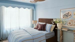 a bedroom with a bed with blue walls and a window at Designed By Three Birds Renovation in Pearl Beach