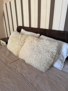 a white furry pillow on a bed with pillows at M Premium Apartments in Paraćin