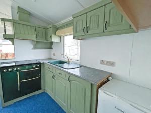a kitchen with green cabinets and a sink at Minster - Uk51005 in Eastchurch