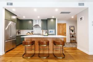 a kitchen with green cabinets and a bar with stools at Inspired Elegance at Tamarack Lodge in Canmore