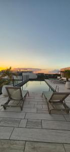 a pool with two chairs and a table on a building at Tuk Tulum Estudio con Balcon 005 in Tulum