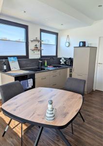 a kitchen with a wooden table and chairs and a table at Haus Ausreißer 2 - Hafennest in Bensersiel